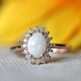Anillo vintage de oro rosa con ópalo ovalado y borde de cristal radiante